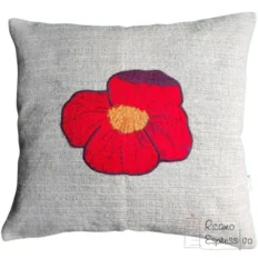 Cuscino beige in policotone pesante arricchito da un papavero rosso ricamato con la tecnica dell'applique, simbolo di semplicità e di consolazione.
