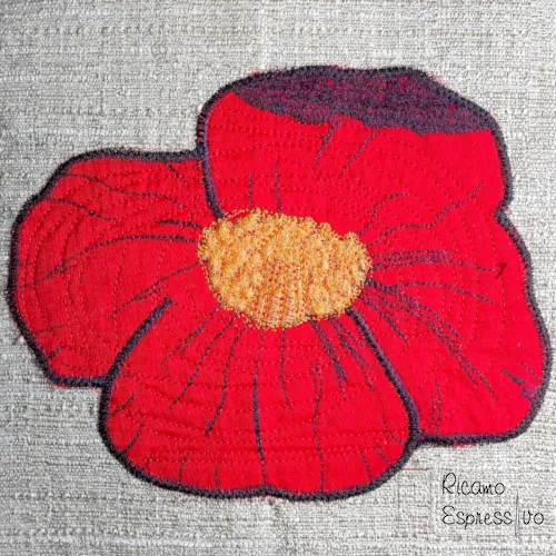 Cuscino beige in policotone pesante arricchito da un papavero rosso ricamato con la tecnica dell'applique, simbolo di semplicità e di consolazione.
